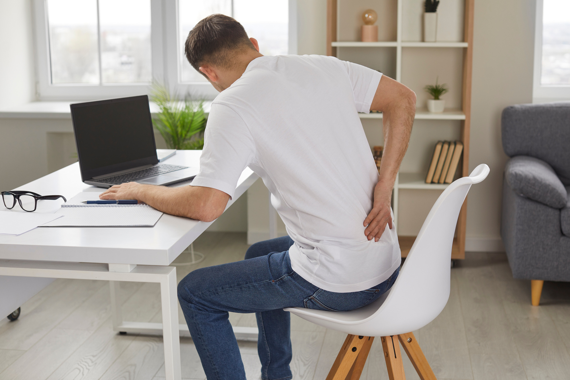 Man Experiences Severe Back Pain Caused by Prolonged and Incorrect Sitting at Workplace.